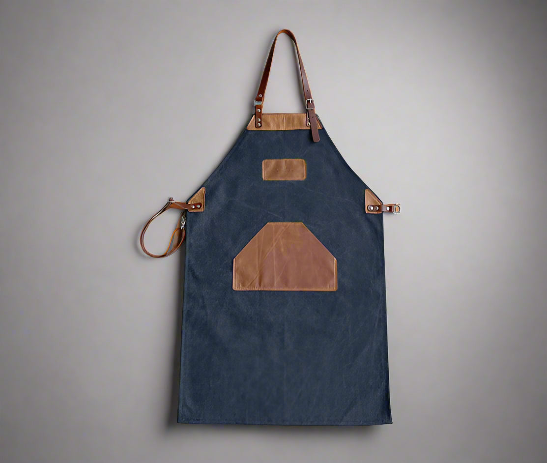 Black and tan canvas and leather apron with adjustable cross-back straps and utility pockets, handmade in Cape Town. Available for custom branding.
