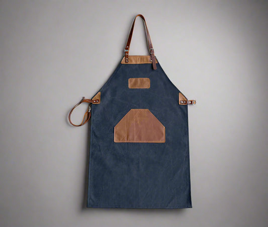 Black and tan canvas and leather apron with adjustable cross-back straps and utility pockets, handmade in Cape Town. Available for custom branding.