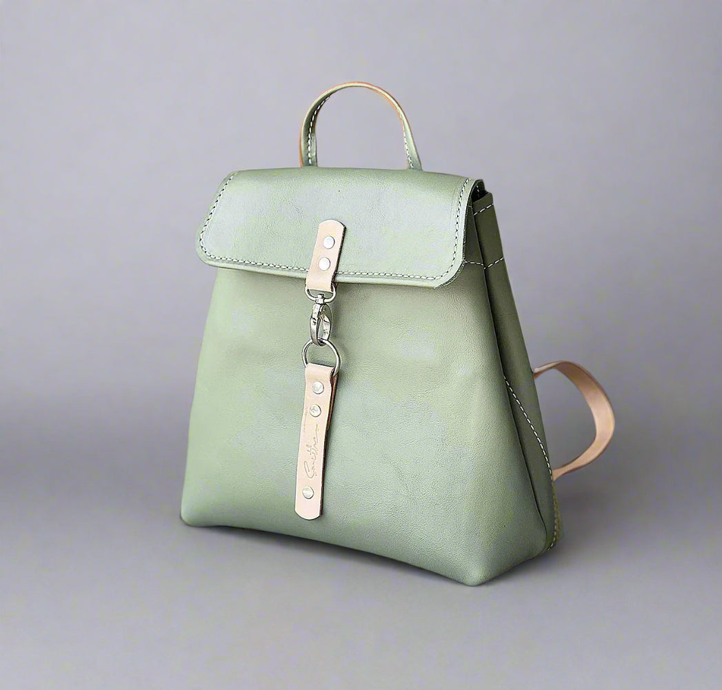 Compact full grain leather backpack in sage green with natural detail with sturdy veg tan shoulder straps and a secure outer easy access pocket. Handmade by women in Cape Town.