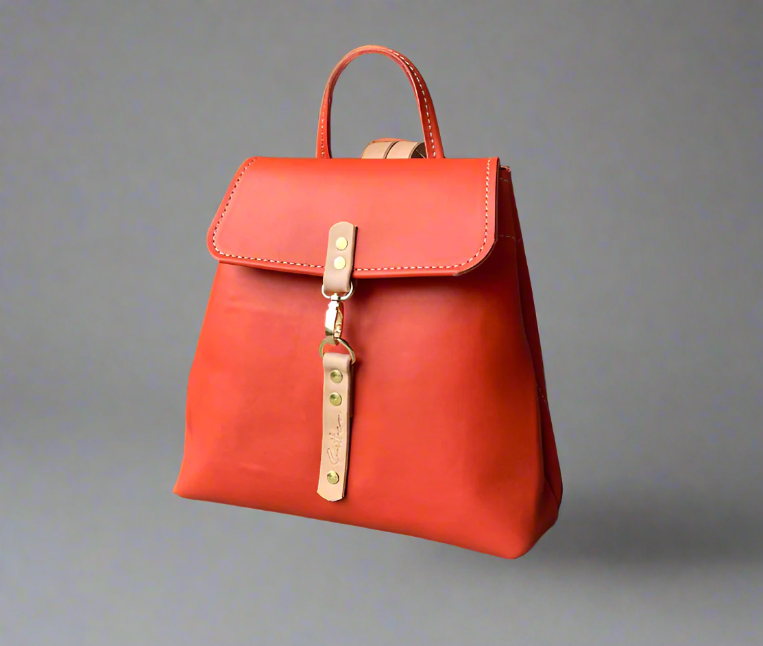 Compact full grain leather backpack in coral orange and natural detail with sturdy veg tan shoulder straps and a secure outer easy access pocket. Handmade by women in Cape Town.