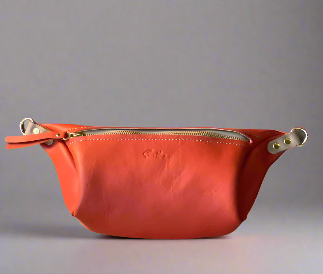 Coral orange full grain leather Moonsling crossbody bag with curved shape and adjustable strap, handmade in Cape Town