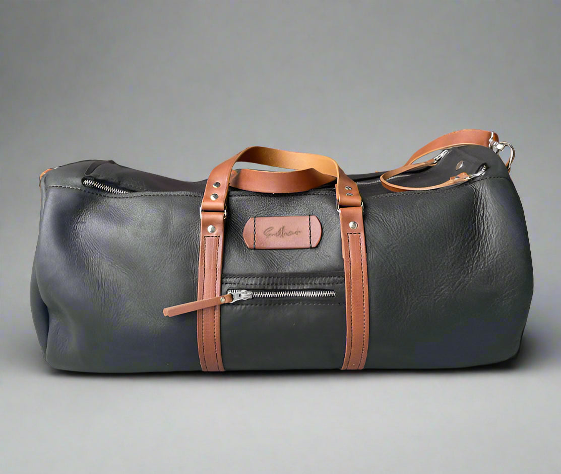 Spacious full grain leather weekend duffel bag in black with tan details, with sturdy handles and detachable strap, handmade in Cape Town