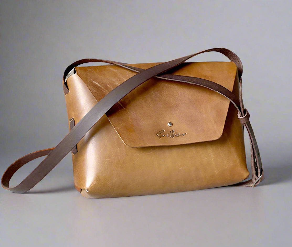 Smooth full grain hand-dyed leather crossbody bag with raw edges and no stitching, handmade in Cape Town. Available in tan and brown.
