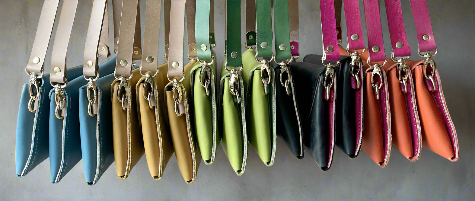 A row of colourful crescent clutches in full grain leather