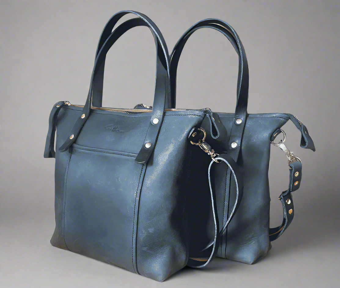 Black coloured mini tote bag in full grain leather with gold fittings and a crossbody strap