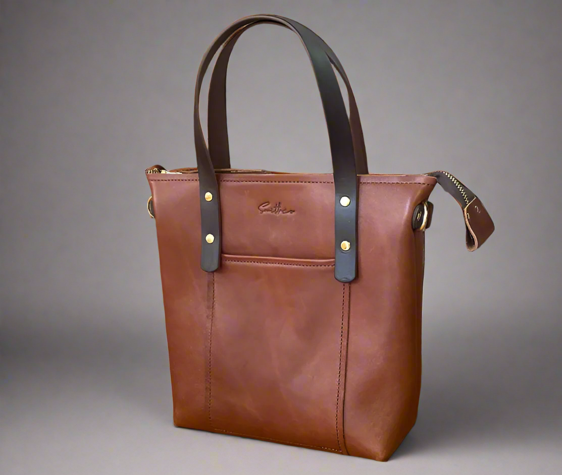Tan coloured mini tote bag in full grain leather with gold fittings and a crossbody strap