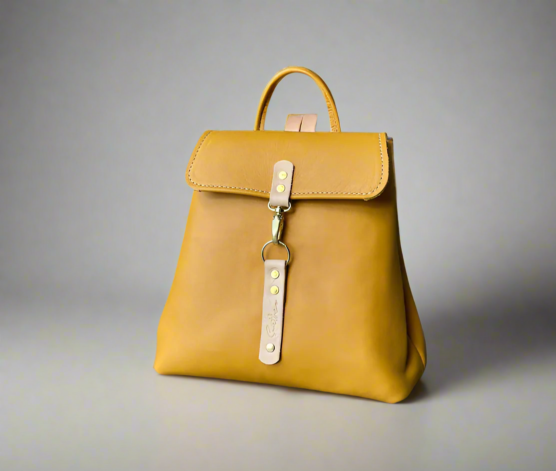 Compact full grain leather backpack in ochre yellow with natural detail with sturdy veg tan shoulder straps and a secure outer easy access pocket. Handmade by women in Cape Town.