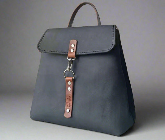 Compact full grain black and tan leather backpack with sturdy veg tan shoulder straps and a secure outer easy access pocket. Handmade by women in Cape Town.