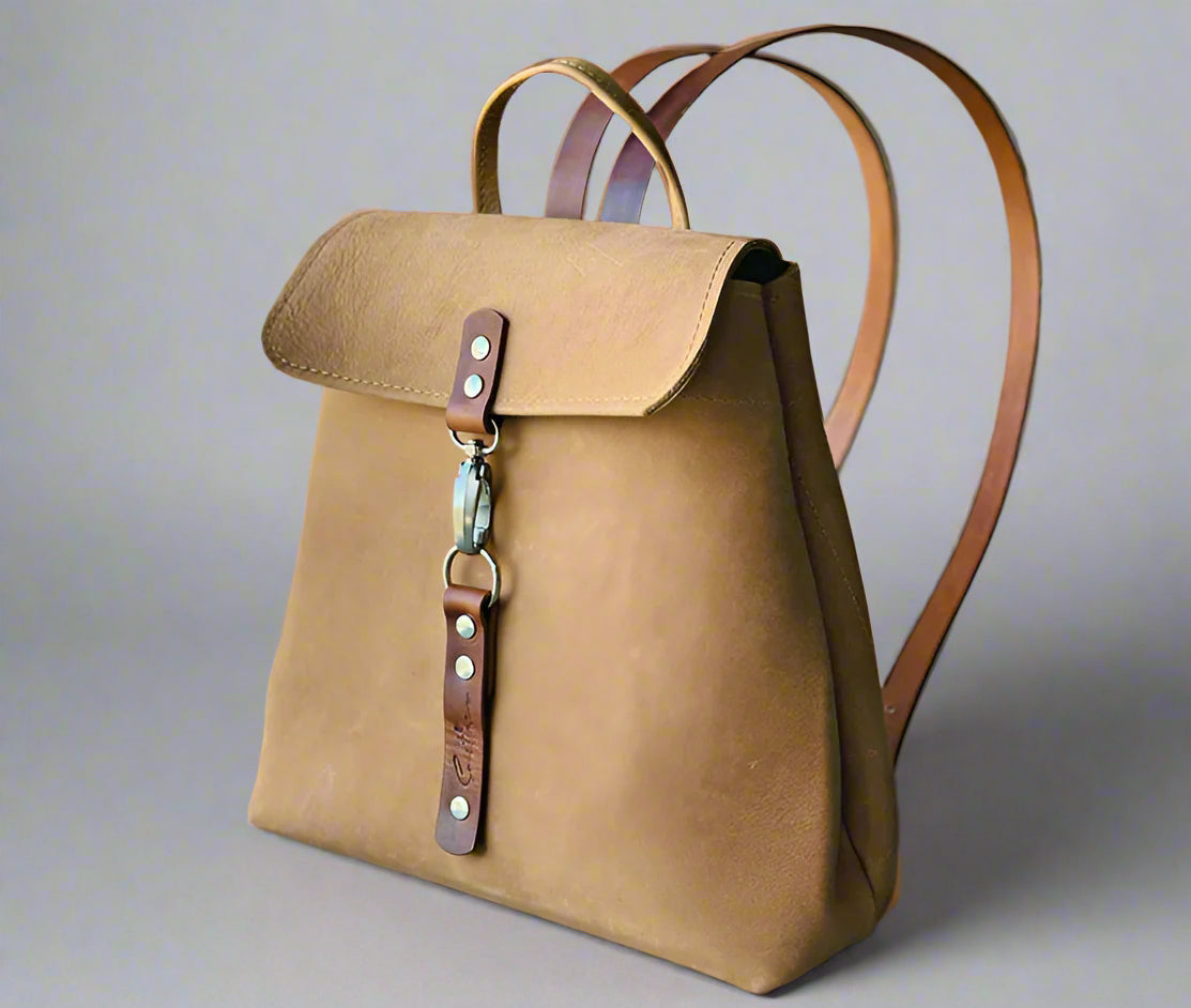 Compact full grain fudge and tan leather backpack with sturdy veg tan shoulder straps and a secure outer easy access pocket. Handmade by women in Cape Town.