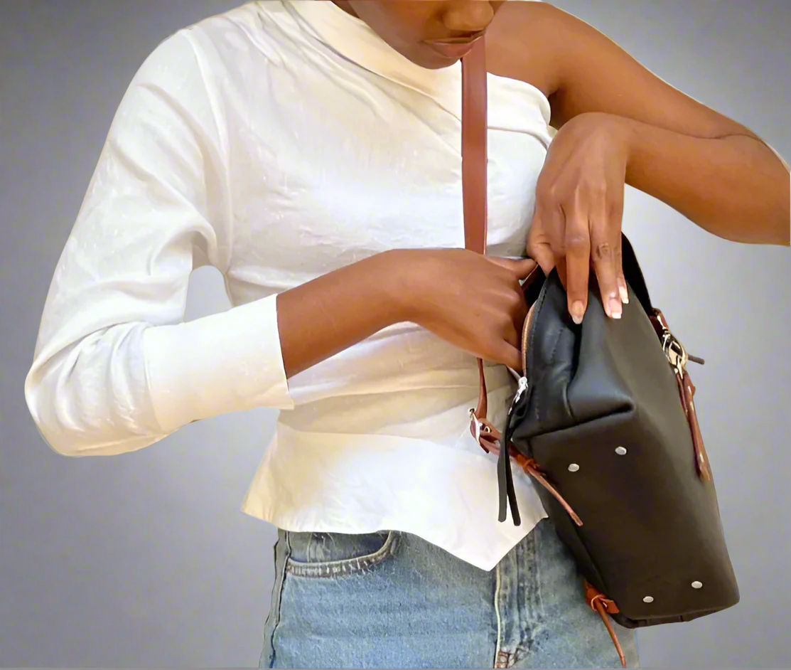 Model showing the secure zipped pocket of the black and tan Smithco Leather backpack