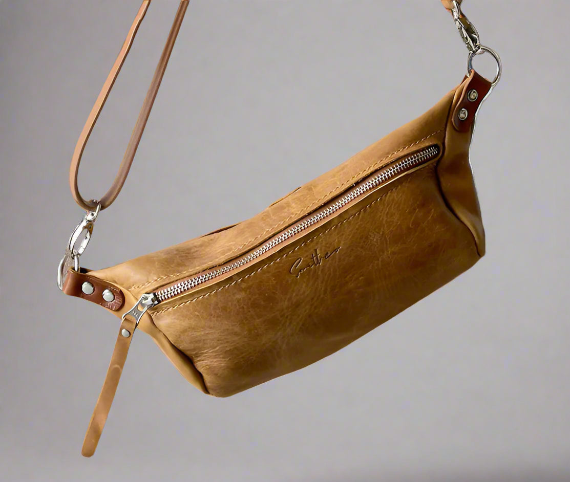 Toffee coloured full grain leather Moonsling crossbody bag with curved shape and adjustable strap, handmade in Cape Town