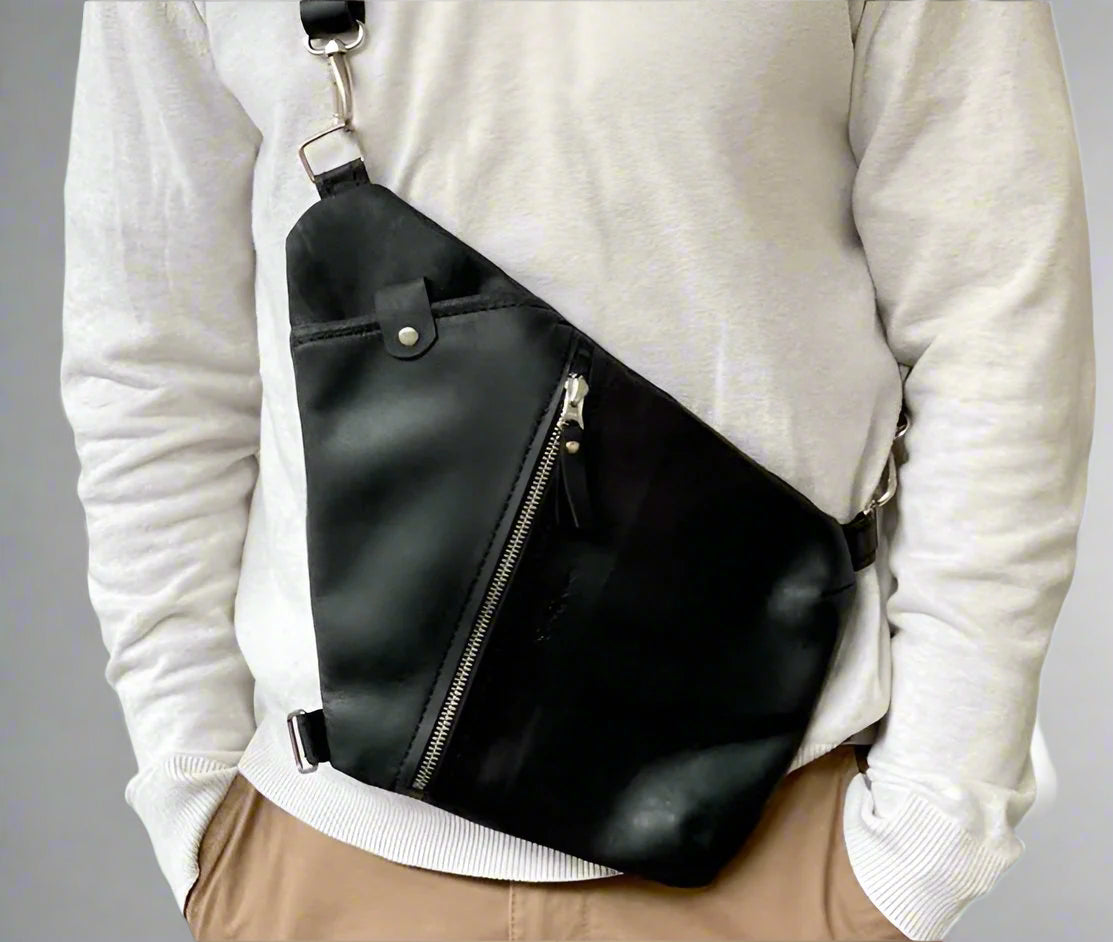 Model wearing a full grain leather travel bag in black. The body hugging design keeps all your essentials secure. Handmade in Cape Town by women.