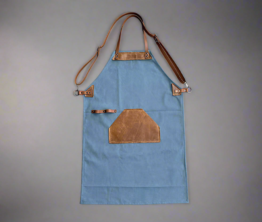 Blue and tan canvas and leather apron with adjustable cross-back straps and utility pockets, handmade in Cape Town. Available for corporate branding.