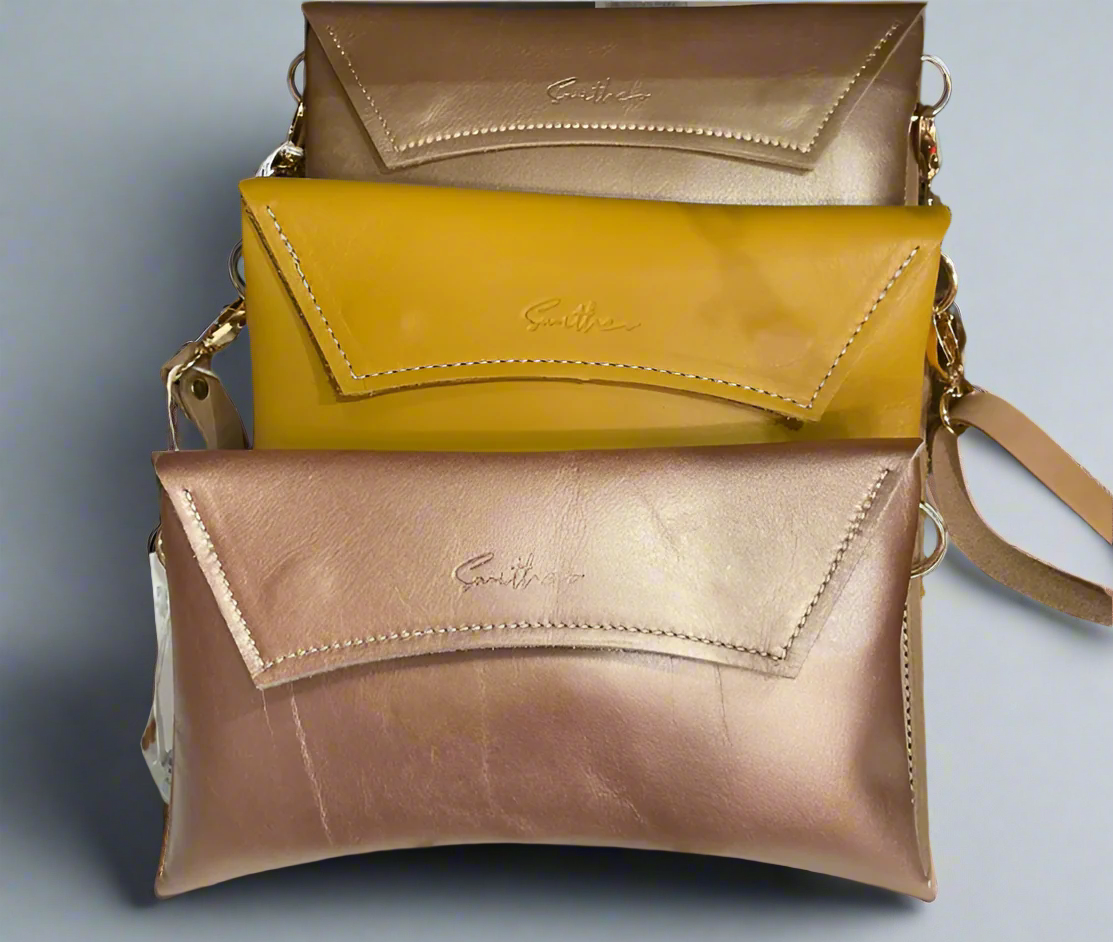 A collection of 3 crescent clutches in rose gold, ochre yellow and gold full grain leather
