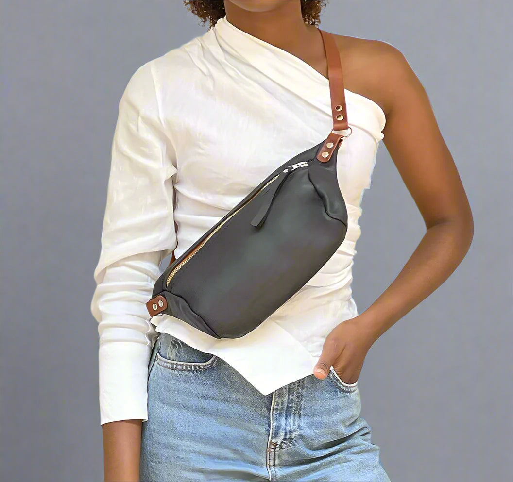 Person wearing a black and tan full grain leather Moonsling crossbody bag with curved shape and adjustable strap, handmade in Cape Town
